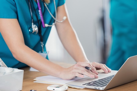 standing female nurse typing on laptop