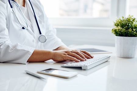 female clinician hands typing at desk in office