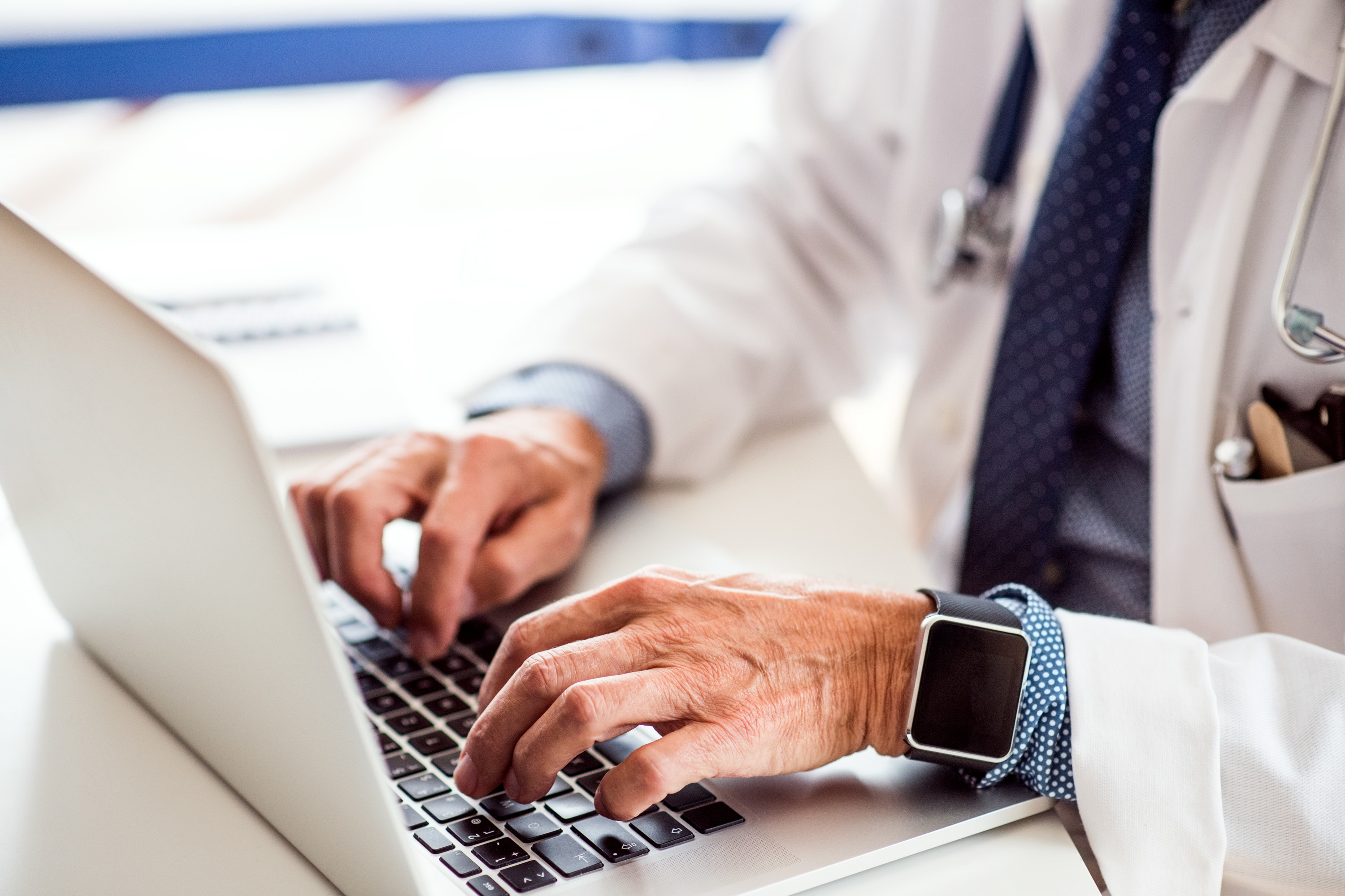 Male doctor with laptop typing on laptop 