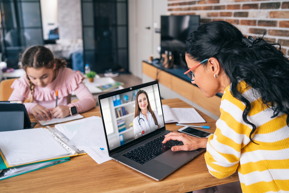 Mom working at home with daughter video call with doctor