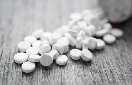 white pills pouring out of bottle onto table