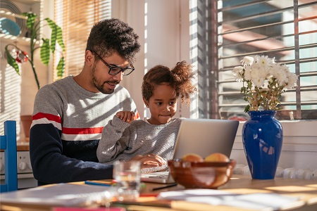 father and daughter looking at tablet in kitchen