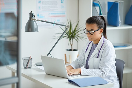 female clinician typing on laptop in office