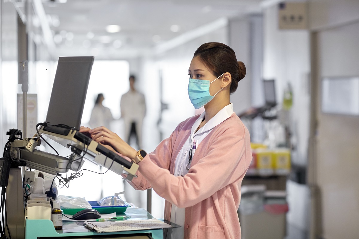 Women wearing a surgical mask typing on a laptop 