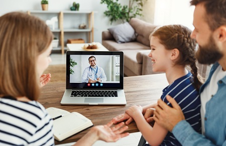 family having virtual visit with doctor on laptop