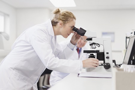 woman looking through telescope in laboratory