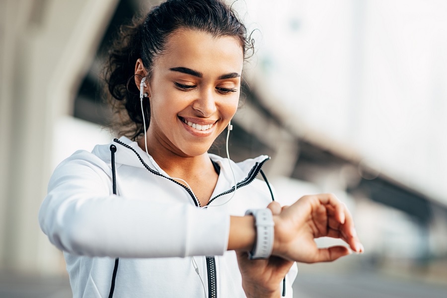young woman in athletic clothes is looking at her smartwatch